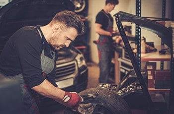 Senior mechanic repairing a car in a garage.