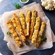 gluten-free-cheese-cauliflower-breadsticks-cheese-breadsticks-with-herbs-parchment-paper 1